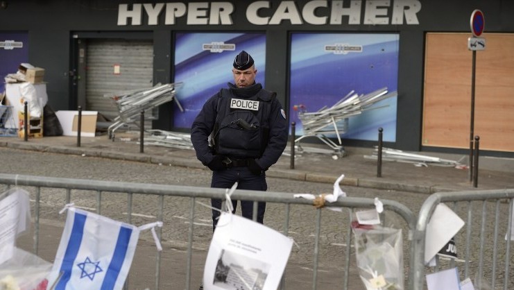 Un policier montant la garde le 21 janvier 2015 devant le magasin HyperCacher à Paris où quatre Juifs ont été  assassinés par Amédy Coulibaly, le 9 janvier 2015. (Crédit : Eric Feferberg/AFP)