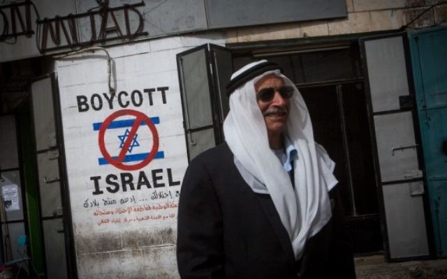 Un Palestinien passe à côté d'une affiche prônant le boycott d'Israël dans la ville de Bethléem en Cisjordanie le 11 février 2015 (Crédit : Miriam Alster/Flash90)
