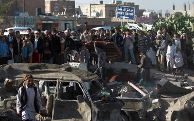 La population yéménite et les forces de sécurité se tiennent sur le site d'une frappe aérienne menée contre les Houthis près de l'aéroport de Sanaa le 26 mars 2015, qui a tué au moins 13 personnes. (Crédit : AFP PHOTO / MOHAMMED HUWAIS)