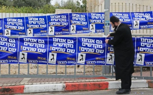 Un partisan ultra-orthodoxe de YaHadout HaTorah vu en train d'accrocher des affiches de campagne dans la ville de Beit Shemesh,  le 17 mars, 2015. (Crédit : Yaakov Naumi / FLASH90)