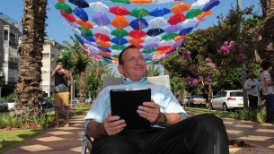 Le maire de Tel-Aviv, Ron Huldai, surfe sur Internet sous le toit de 600 parasols colorés qui décorent le boulevard Rothschild pour lancer le nouveau « cloud Wi-Fi » dans sa ville (Crédit : Kfir Sivan)