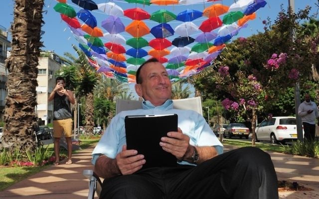Le maire de Tel-Aviv, Ron Huldai, surfe sur Internet sous le toit de 600 parasols colorés qui décorent le boulevard Rothschild pour lancer le nouveau « cloud Wi-Fi » dans sa ville (Crédit : Kfir Sivan)