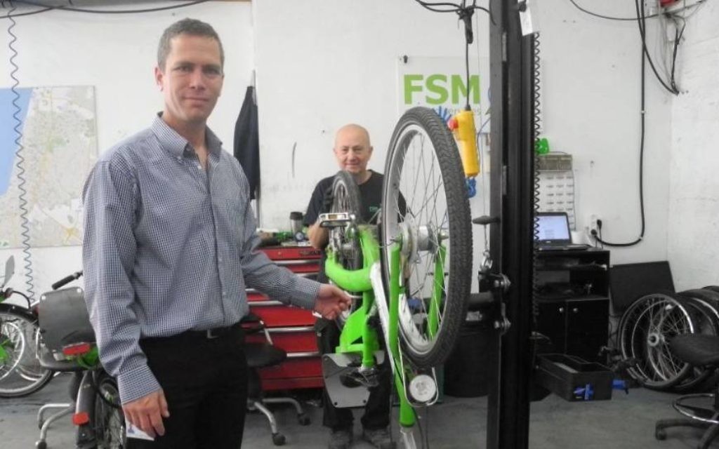 Ofer Sela, le PDG de FSM, un conglomérat d'entreprises qui gère Tel-O-Fun, avec un mécanicien de vélo à Tel Aviv. (Crédit : Melanie Lidman / Times of Israël)