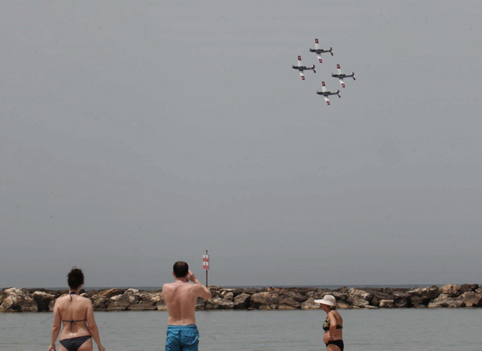 Les baigneurs sur la plage de Tel Aviv regardent l'équipe acrobatique aérienne de l'armée de l'air israélienne le 20 avril 2015 pendant qu'ils se préparent pour le spectacle du 67e anniversaire du Jour de l'Indépendance d'Israël. (Crédit : Flash90)