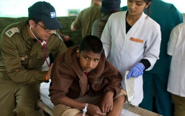 Un médecin militaire israélien soigne un garçon népalais à l'hôpital de campagne israélien de Katmandou, le 30 avril 2015. (Crédit : AFP/Menachem Kahana)