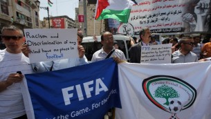 Des Palestiniens qui tiennent des bannières pendant une  manifestation dans le centre de la ville de Ramallah en Cisjordanie, demandant l'expulsion d'Israël de l'organe mondial du football, la FIFA, le 19 mai 2015  (Crédit :AFP PHOTO / ABBAS MOMANI)