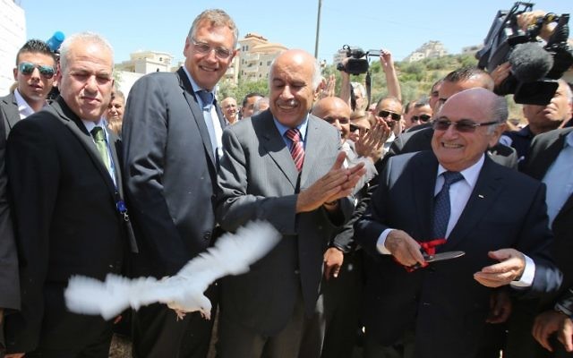 La président de la FIFA, Joseph Blatter (à droite) libère une colombe tandis que le président de l'Association de football palestinien, Jibril Rajoub (au centre) applaudit lors de sa visite au village de Dura al-Qaraa, près de la ville cisjordanienne de Ramallah, le 20 mai 2015. (Crédit : AFP / ABBAS MOMANI)