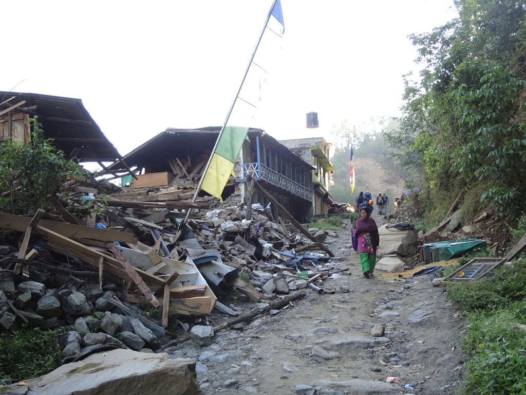 Une femme passe sous un cordon de drapeaux de prière dans le village détruit de Topani, dans le district durement touché de Sidhulpalchowk à 7 heures de route de Katmandou, au Népal, mai 2015 (Crédit : Melanie Lidman / Times of Israël)