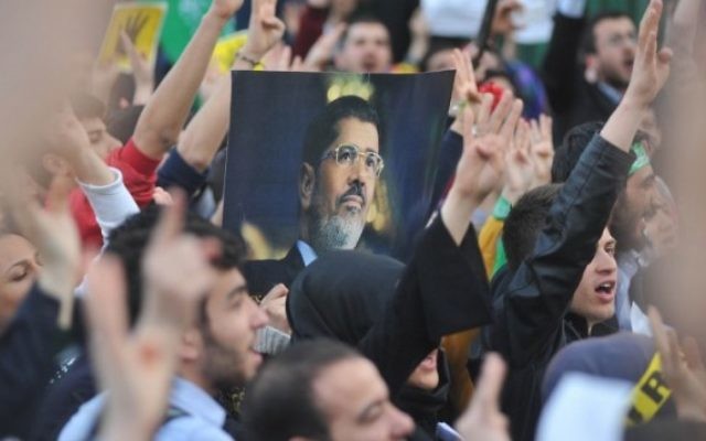 Les partisans des Frères musulmans avec un portrait du président déchu Mohammed Morsi tandis qu'ils prennent part à un rassemblement pour protester contre les peines de mort pour des membres du groupe radical en Egypte, devant l'ambassade égyptienne à Ankara, le 9 avril 2014. (Crédit : AFP PHOTO / ADEM ALTAN)