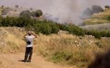 Un Druze observant les bombardements entre les forces syriennes depuis le côté israélien de la frontière avec la Syrie sur le plateau du Golan, le 16 juin 2015. (Crédit : Basel Awidat/Flash90)