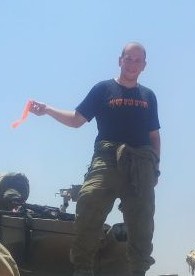Alon Haidu se tient sur un char, vêtu d'une chemise qui dit "retour à Gush Katif" (Crédit : Autorisation)
