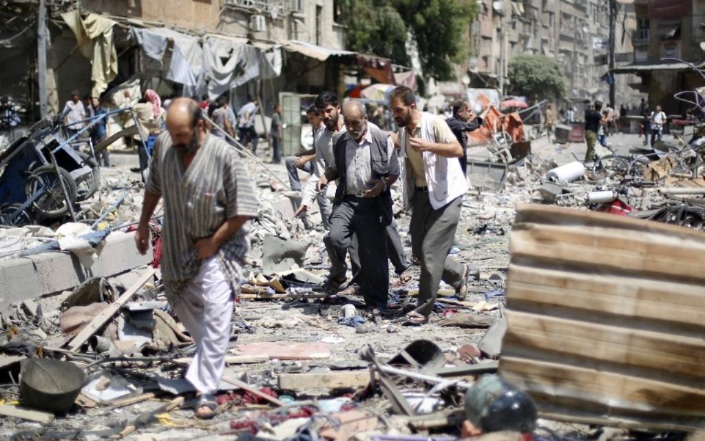 Des Syriens marchent au milieu des décombres de frappes aériennes des forces gouvernementales syriennes sur un marché, à Douma, zone contrôlée par les rebelles, à l'est de Damas, le 16 août 2015. (Sammer al Doumy / AFP)