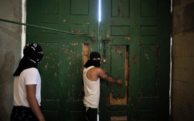 Les Palestiniens masqués sécurisant la porte de la mosquée al-Aqsa le 27 septembre 2015 (Crédit : AFP PHOTO / AHMAD GHARABLI)