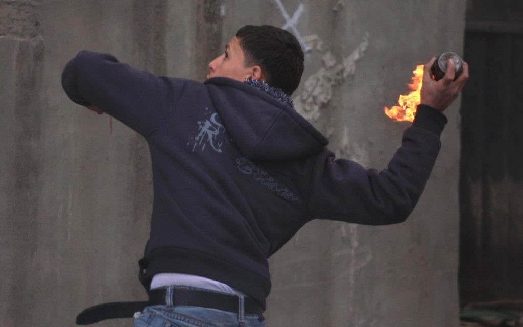 Un Palestinien jette une bombe incendiaire (Crédit : Issam Rimawi / Flash90)