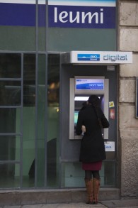 Une femme se tient devant un guichet automatique à Jérusalem (Crédit: Yonatan Sindel / Flash90)