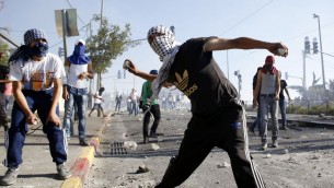 Des émeutiers palestiniens masqués jetant des pierres sur la police israélienne lors d'affrontements dans le quartier de Shuafat à Jérusalem-Est, le 3 juillet 2014 (Crédit photo: Sliman Khader / Flash90)
