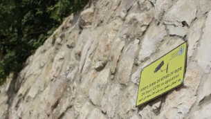 Un panneau d'avertissement pour les lanceurs de pierre qui indique que la zone est sous surveillance sur le mur séparant Armon Hanatziv de Jabel Mukaber, le 16 septembre 2015. (Crédit : Juda Ari Gross / Times of Israël)