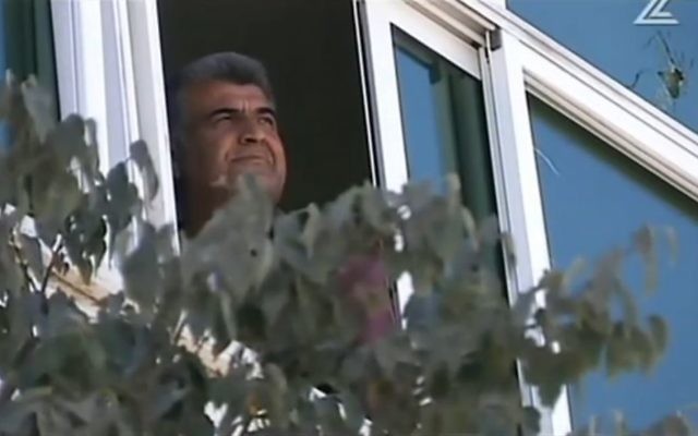 Faiz Abu Hamadia regardant par la fenêtre de sa maison à Hébron. Abu Hamadia a sauvé cinq étudiants d'une yeshiva qui sont accidentellement entrés dans la ville et sont devenus les victimes d'émeutes Palestiniennes (Crédit : Capture d'écran Deuxième chaîne)