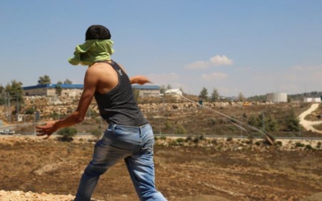 Un Palestinien du village de Nabi Saleh, en Cisjordanie, lance une pierre à l'aide d'une fronde sur des soldats israéliens, le 28 août 2015. Illustration. (Crédit : Eric Cortellessa/Times of Israël)