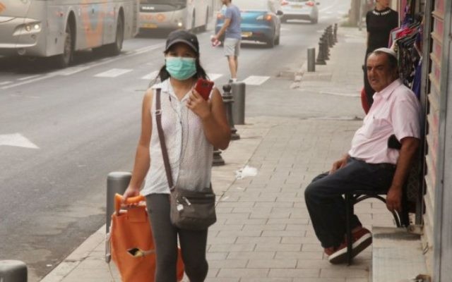 Une femme portant un masque devant sa bouche lors d'une journée poussiéreuse à Tel Aviv le 9 septembre 2015 (Crédit photo: Flash90)