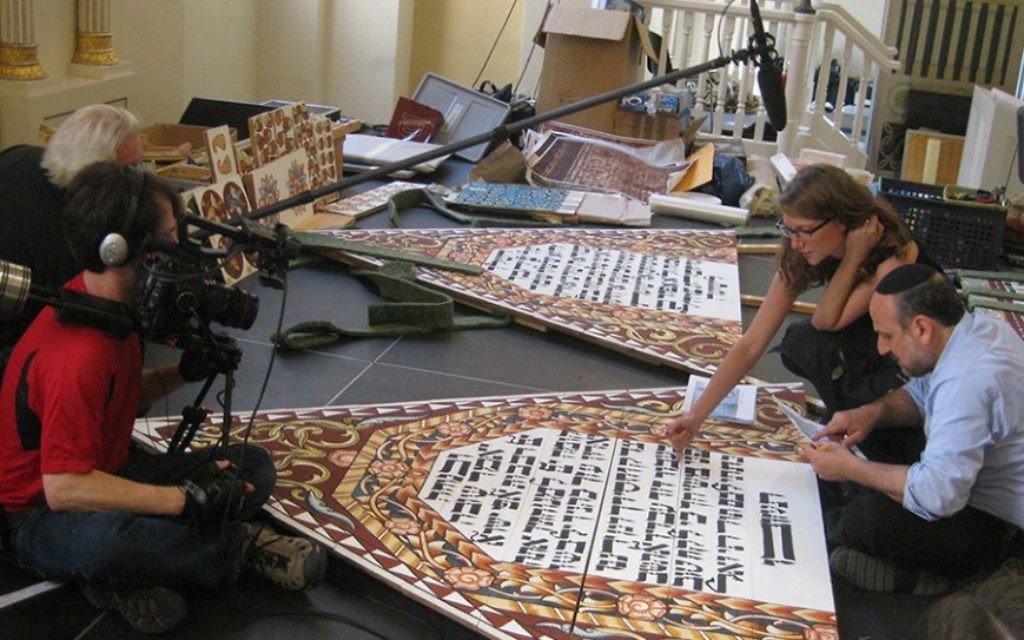 Yari et Cary Wolinsky tournant la calligraphie et la peinture pendant qu'Ariel Rosenblum examine le texte hébreu avec le rabbin Michael Schudrich, le Grand Rabbin de Pologne (Crédit : Trillium Studios production)