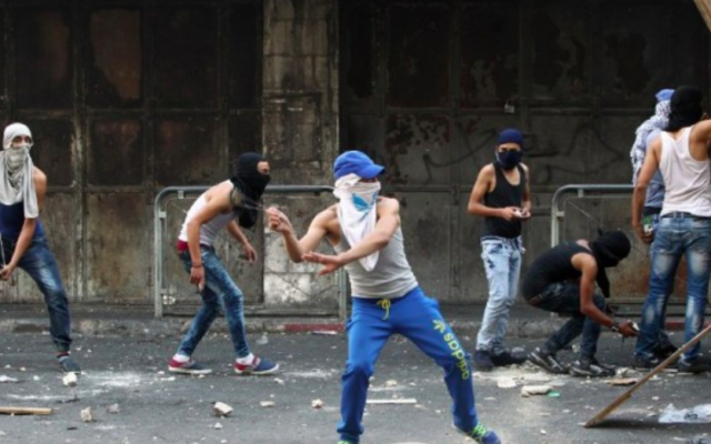De jeunes Palestiniens lancent des pierres vers les forces de sécurité israéliennes lors d'affrontements dans la ville d'Hébron en Cisjordanie, le 4 octobre, 2015. (Crédit : AFP / HAZEM BADER)