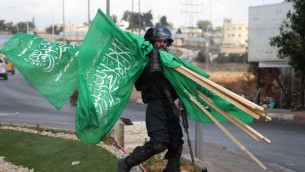 Un membre des forces de sécurité israéliennes porte  des drapeaux de l'organisation terroriste du Hamas qui ont été saisis lors d'affrontements avec des manifestants palestiniens près de limplantation de Beit El en Cisjordanie, le 8 octobre 2015 (Credit photo: Abbas Momani / AFP)