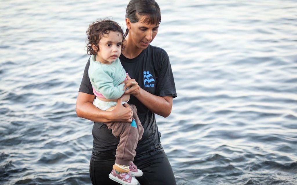Tali Shaltiel, 31 ans, médecin à Jérusalem, de l'eau jusqu'aux genoux, aide une petite fille de quatre ans (Crédit : JTA)