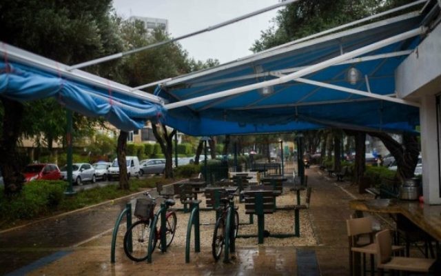 Chaises vides dans un café en plein air sur le boulevard Ben Gourion alors qu'un orage s'abat sur Tel Aviv, le 25 octobre 2015 (Crédit photo: Ben Kelmer / Flash90)
