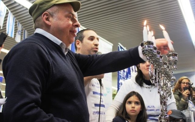 Le président de l'Agence juive, Nathan Sharansky rejoint la famille Ammar pour allumer la troisième bougie de Hanukka pendant une cérémonie d'accueil de dizaines d'immigrants juifs de France en Israël, le 8 décembre 2015. (Crédit : Nathan Roi/Agence juive pour Israël)