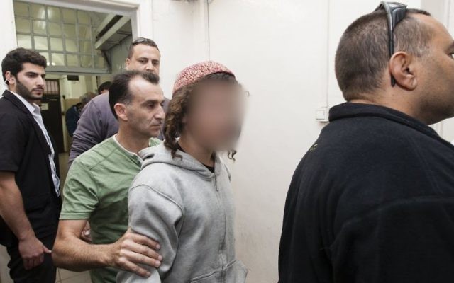 Un jeune extrémiste juif présumé escorté par la police à la Cour de Jérusalem pour des soupçons d'incendie dans une maison à Sinjil, un village en Cisjordanie, en novembre 2013. (Crédit : Flash90)