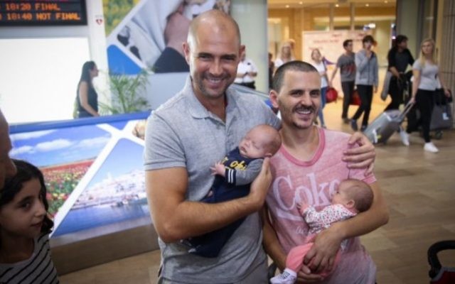 Le député du Likud Amir Ohana (à gauche) et son partenaire à l'aéroport international Ben Gourion, de retour des États-Unis avec leurs bébés nés par mère porteuse, le 26 septembre 2015. (Crédit : Flash90)