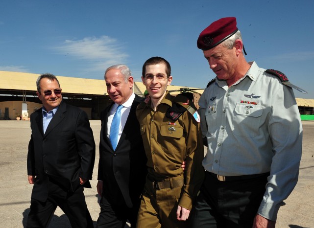Le soldat israélien Gilad Shalit libéré (deuxième à droite), avec le Premier ministre Benjamin Netanyahu (deuxième à gauche), le ministre de la Défense de l'époque Ehud Barak (à gauche), et l'ex-chef d'état major, le lieutenant général Benny Gantz (à droite), à la base aérienne de Tel  Nof dans le sud d'Israël, le 18 octobre 2011 (Crédit : Ariel Hermoni / Ministère de la Défense / Flash90)
