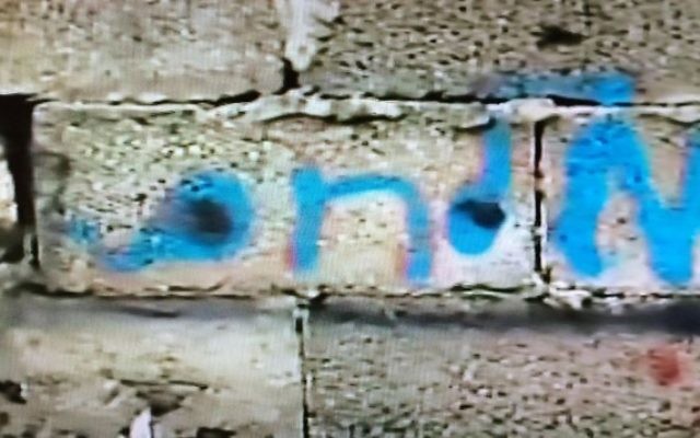 Le nom de famille en hébreu "Milhem" écrit en bleu sur le mur extérieur du dernier bâtiment dans lequel le tireur de Tel Aviv, Nashat Milhem, s'est caché à Arara avant d'être retrouvé, pourchassé et tué le 8 janvier 2016. (Crédit : capture d'écran Deuxième chaîne)