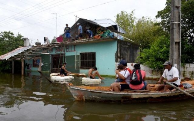 Des habitants naviguent le long des rues inondées d’Asunción, le 4 janvier 2016. Jusqu'à présent, six personnes sont mortes, et plus de 100 000 ont été déplacées, 25 766 familles sont dans des refuges, 125 000 foyers sont privés de courant électrique. (Crédit : AFP PHOTO/NORBERTO DUARTE)