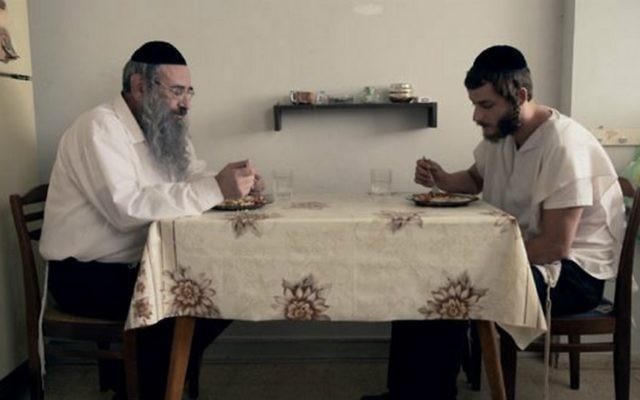 Les Shtisel, le père Shulem et le fils Akiva, à table dans leur cuisine (Crédit : "Shtisel")