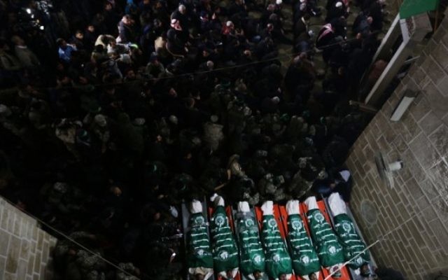 Des combattants du Hamas se rassemblent autour des corps de sept ouvriers tués dans l'effondrement d'un tunnel dans la bande de Gaza, pendant leurs funérailles, le 29 janvier 2016. (Crédit : AFP/Mahmud Hams)