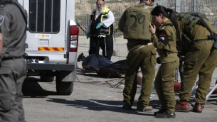 Un volontaire de  Zaka et des membres des forces de sécurité israéliennes près du corps d'un attaquant palestinien abattu à la suite d'une tentative d'attaque au couteau au checkpoint de Har Homa, en Cisjordanie, le 14 février 2016. (Crédit : AFP/AHMAD GHARABLI)