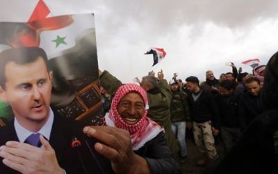 Un volontaire syrien et ses proches brandissent le drapeau national et des portraits du président Bashar el-Assad en célébrant la fin d'un entraînement paramilitaire mené par l'armée syrienne le 22 février 2016. (Crédit : AFP / LOUAI BESHARA)