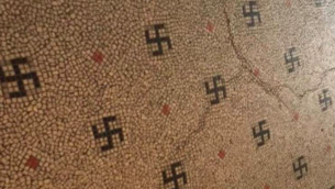 Le sol de l'entrée d'un immeuble du 6e arrondissement de Paris contient des dizaines de croix gammées en mosaïque noire qui sont incorporées au sol. (Crédit : JTA / BNVCA)