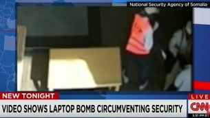 Deux hommes, dont au moins un est un employé de l'aéroport, tendant ce qui ressemble à un ordinateur portable au terroriste kamikaze présumé, après son passage des contrôles de sécurité à l'aéroport de Mogadiscio. (Crédit : capture d'écran YouTube/CNN)