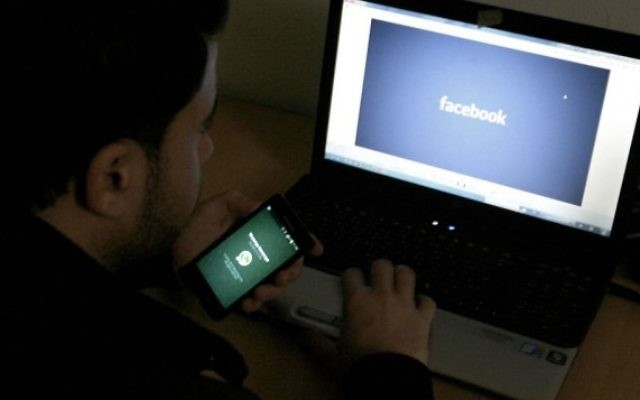 Un homme devant un ordinateur avec un logo Facebook, le 26 février 2016. Illustration. (Crédit : Abed Rahim Khatib/Flash90)