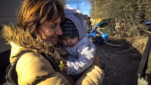 une femme et son enfant dans un camp de réfugiés dans le nord de la France, en février 2016. (Crédit : IsraAID)