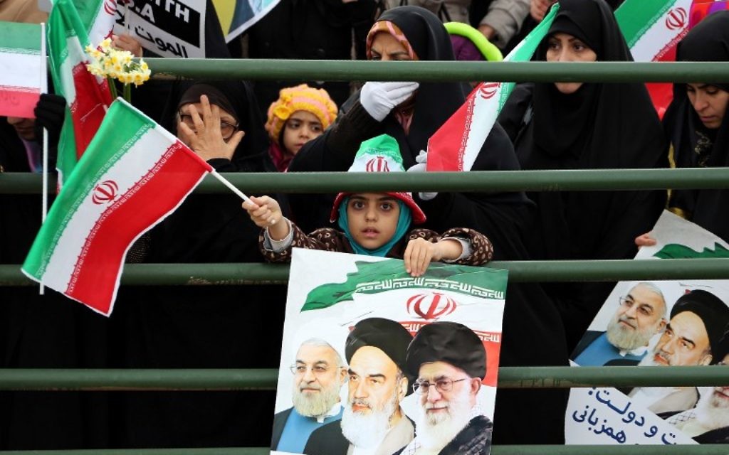 Une jeune fille iranienne tient une affiche avec un portrait du président Hassan Rouhani (à gauche), ledéfunt leader, l'ayatollah Ruhollah Khomeini et l'ayatollah Ali Khamenei, lors des célébrations sur la place Azadi de Téhéran (Place de la Liberté) pour marquer le 37e anniversaire de la révolution islamique le 11 février 2016 (Crédit : AFP / ATTA KENARE)