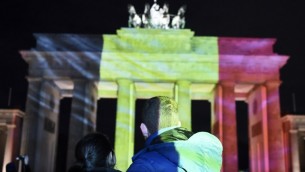 Un couple regarde les couleurs du drapeau belge projetées sur la porte de Brandebourg à Berlin, la capitale allemande montre sa solidarité après les attentats de Bruxelles, le 22 mars 2016. (Crédit : AFP / ODD ANDERSEN)AFP / ODD ANDERSEN)
