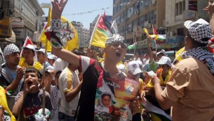 Des Palestiniens avec des affiches et des T-shirts représentant Dalal Mughrabi, une terroriste du Fatah responsable du massacre de la route côtière en 1978, qui a tué 38 Israéliens dont 13 enfants, pendant une manifestation à Ramallah, le 16 juillet 2008. (Crédit : Issam Rimawi/Flash90)