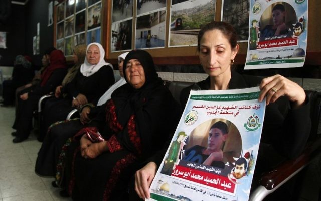 Azhar Abu Srour, la mère d'Abdel Hamid Abu Srour, 19 ans (sur l'affiche), qui a mené un attentat suicide dans un bus de Jérusalem le 18 avril, porte le deuil avec les membres de sa famille et reçoit des condoléances au centre Al-Ruwad du camp de réfugiés d'al-Ayda, le 22 avril 2016. (Crédit : AFP PHOTO / MUSA AL SHAER)