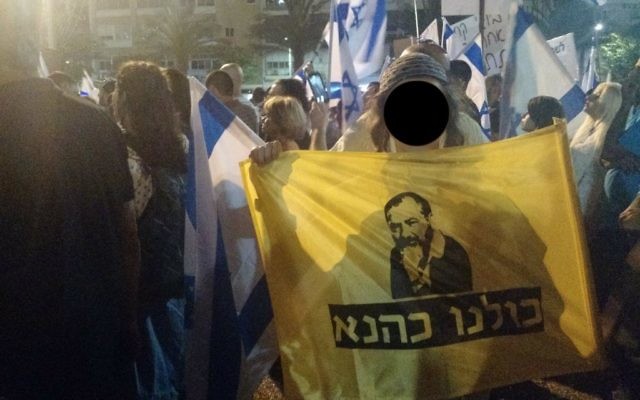 un adolescent avec un drapeau "Nous sommes tous Kahane" pendant un rassemblement  de soutien à un soldat accusé d'avoir tué un attaquant palestinien neutralisé en mars à Hébron, le 19 avril 2016. (Crédit : Judah Ari Gross/Times of Israel)