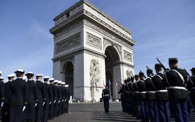 Soldats français devant l'Arc de Triomphe et la flamme du Soldat Inconnu pendant une cérémonie commémorant le 71e anniversaire de la victoire sur l'Allemagne nazie pendant la Seconde Guerre Mondiale, à Paris, le 8 mais 2016. (Crédit : AFP/Lionel Bonaventure)