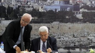 Le président de l'Autorité palestinienne, Mahmoud Abbas (à droite) et le responsable des négociations pour la paix, Saeb Erekat, signent une candidature pour intégrer les organismes de l'ONU, à Ramallah, en Cisjordanie, le mardi 1er avril 2014. (Crédit : Issam Rimawi/Flash90)